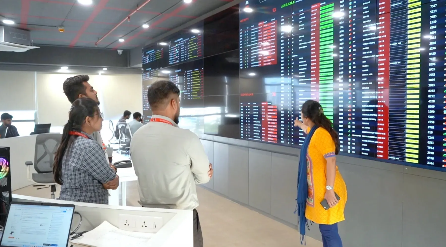 Operators in a control room watching a live fleet board on a video wall
